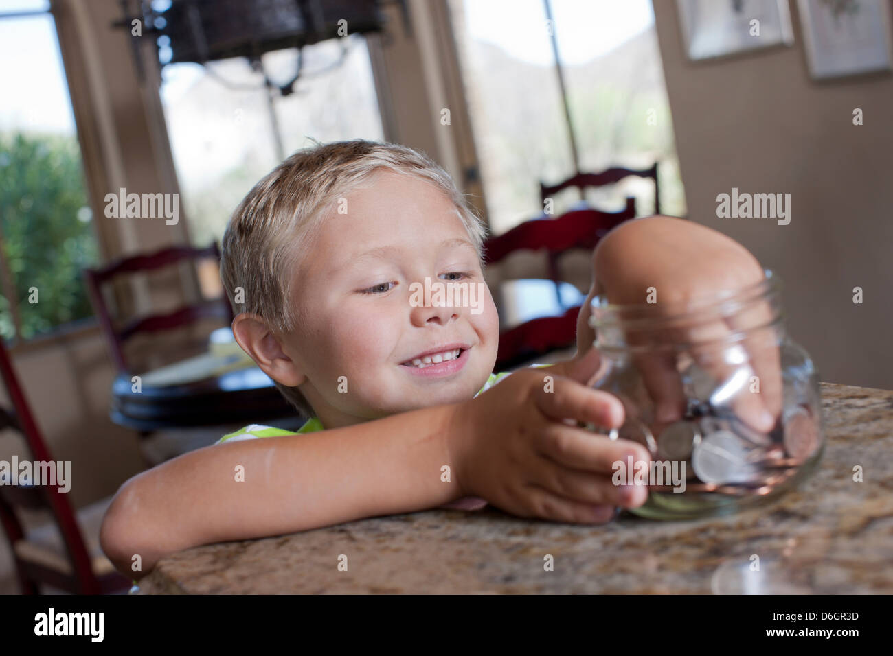 Boy putting savings in glass jar Stock Photo