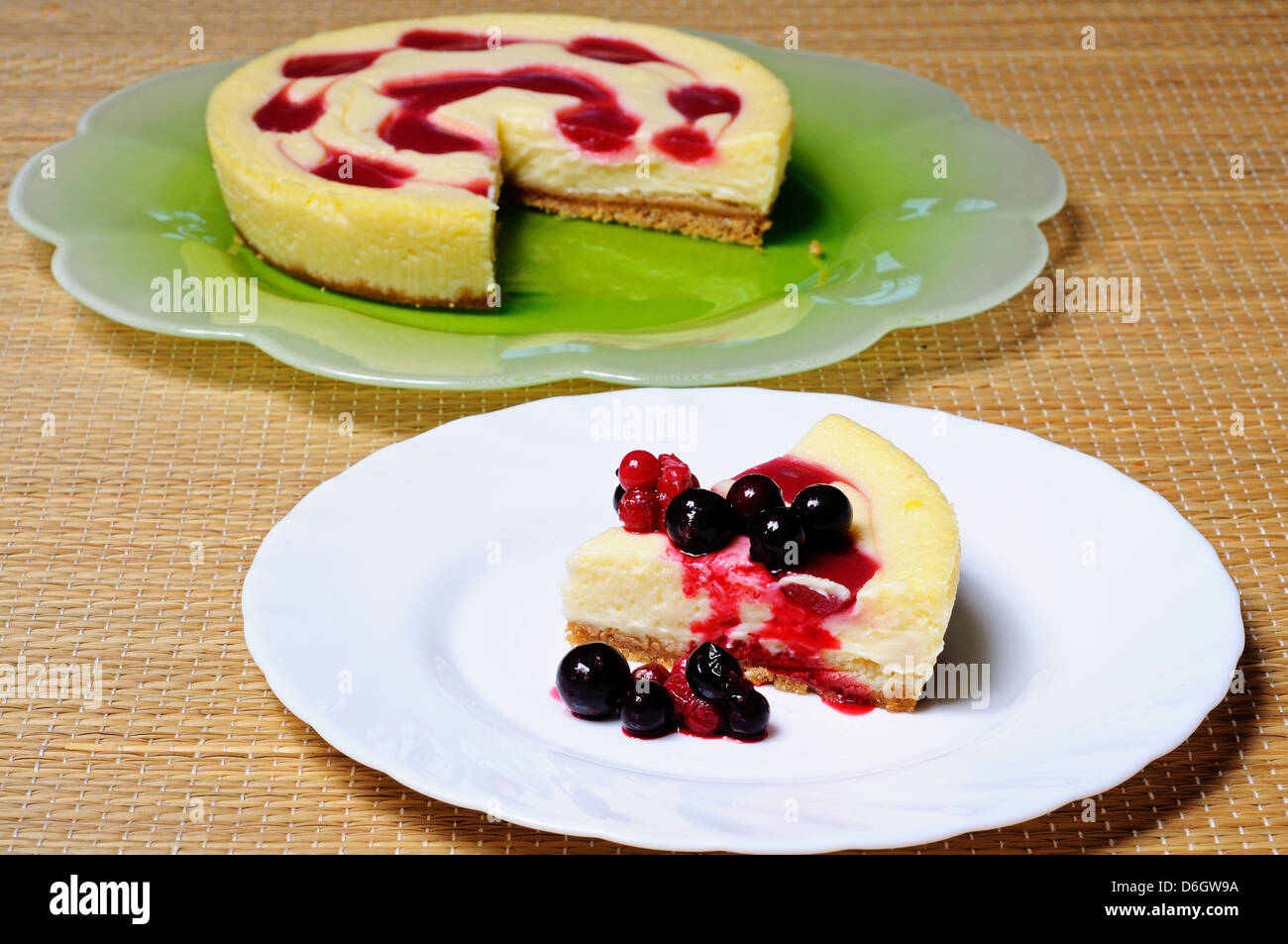 Cheesecake topped with raspberry syrup and fresh red berries. Stock Photo