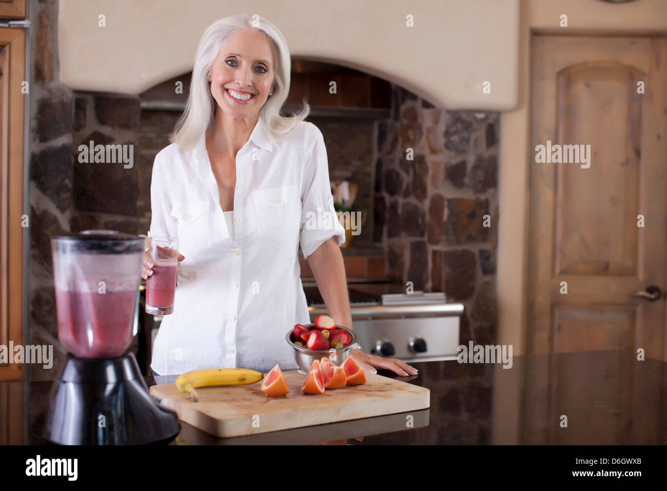 Older woman making smoothie in kitchen Stock Photo - Alamy
