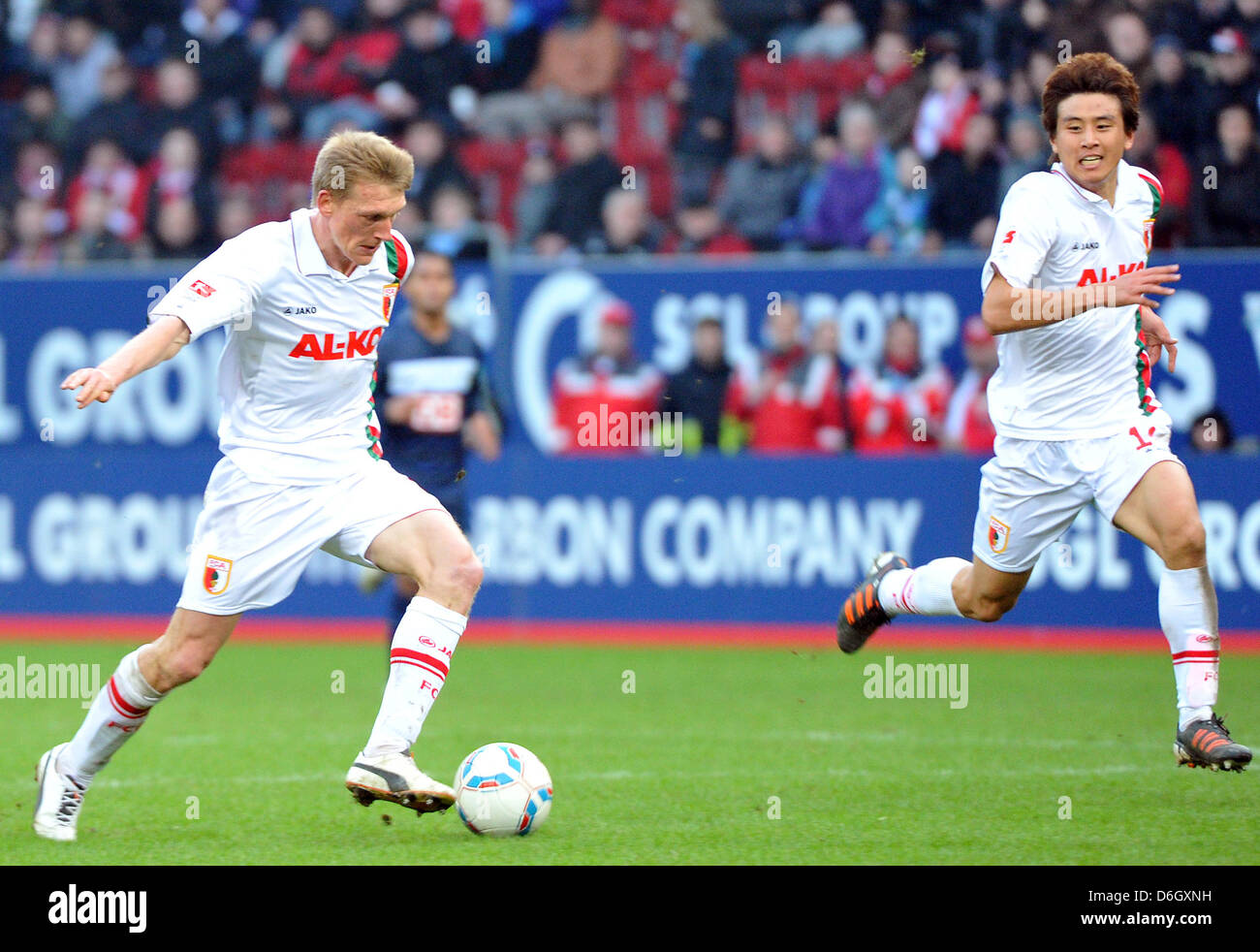 Augsburg's Axel Bellinghausen (L) runs with the ball as he passes his teammate Ja-Cheol Koo during the Bundesliga soccer match between FC Augsburg and Hertha BSC at the SGL-Arena in Augsburg, Germany, 25 February 2012.  Augsburg won the match 3-0. Photo: Stefan Puchner Stock Photo