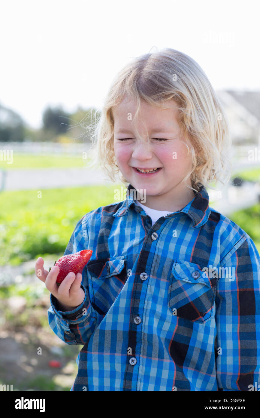 Boy eating strawberry outdoors Stock Photo