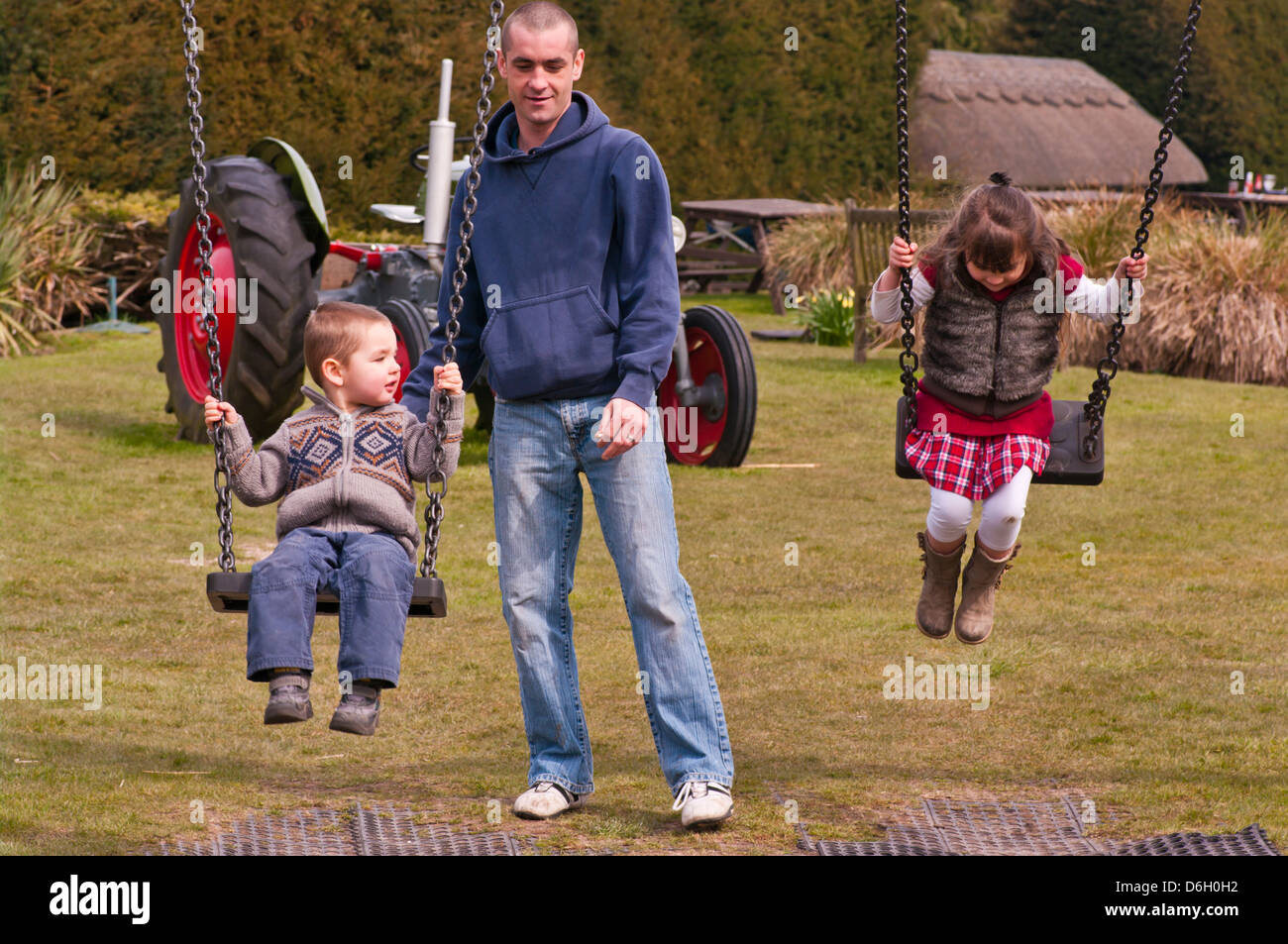 Parent Pushing His Children On Swings Stock Photo Alamy