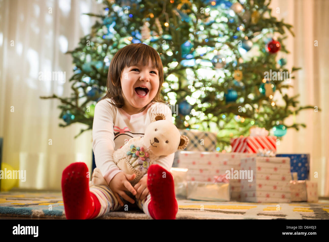 Girl laughing by Christmas tree Stock Photo - Alamy