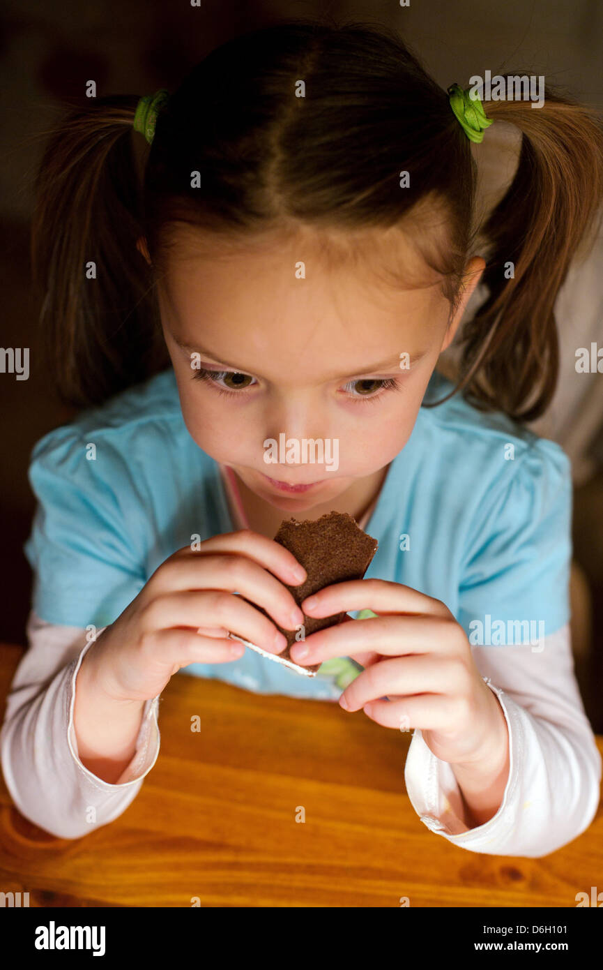 a-five-year-old-girl-eats-candy-at-the-table-of-her-parent-s-home-in