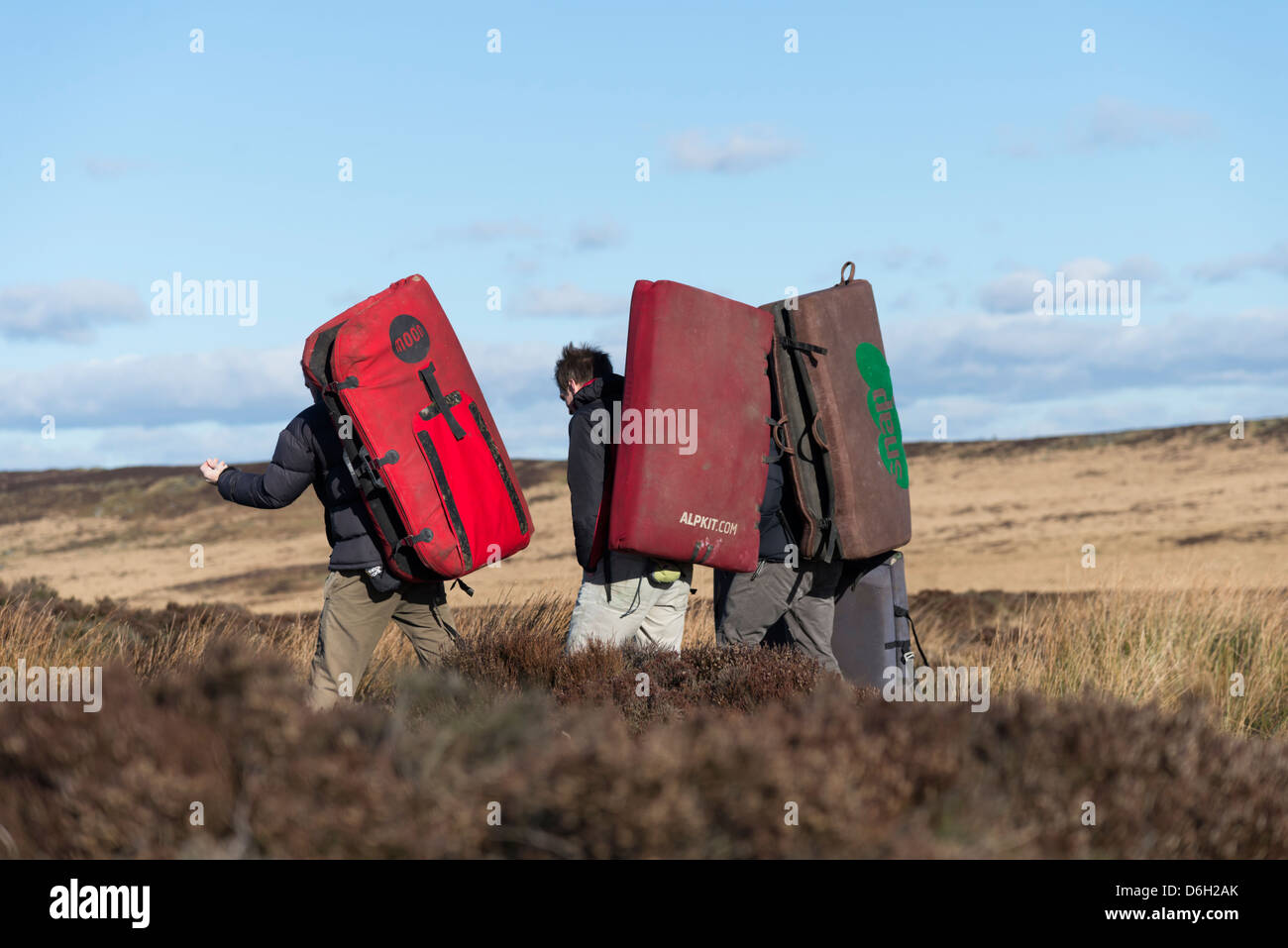 Group of men carrying bouldering mats or crash pads used for safety on short climbs Derbyshire UK Stock Photo