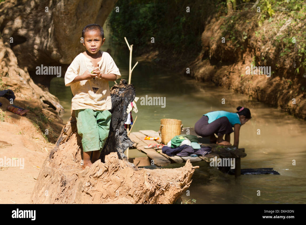 Young boy by a stream whilst his mother does the washing - Inn Thein Village 3 Stock Photo