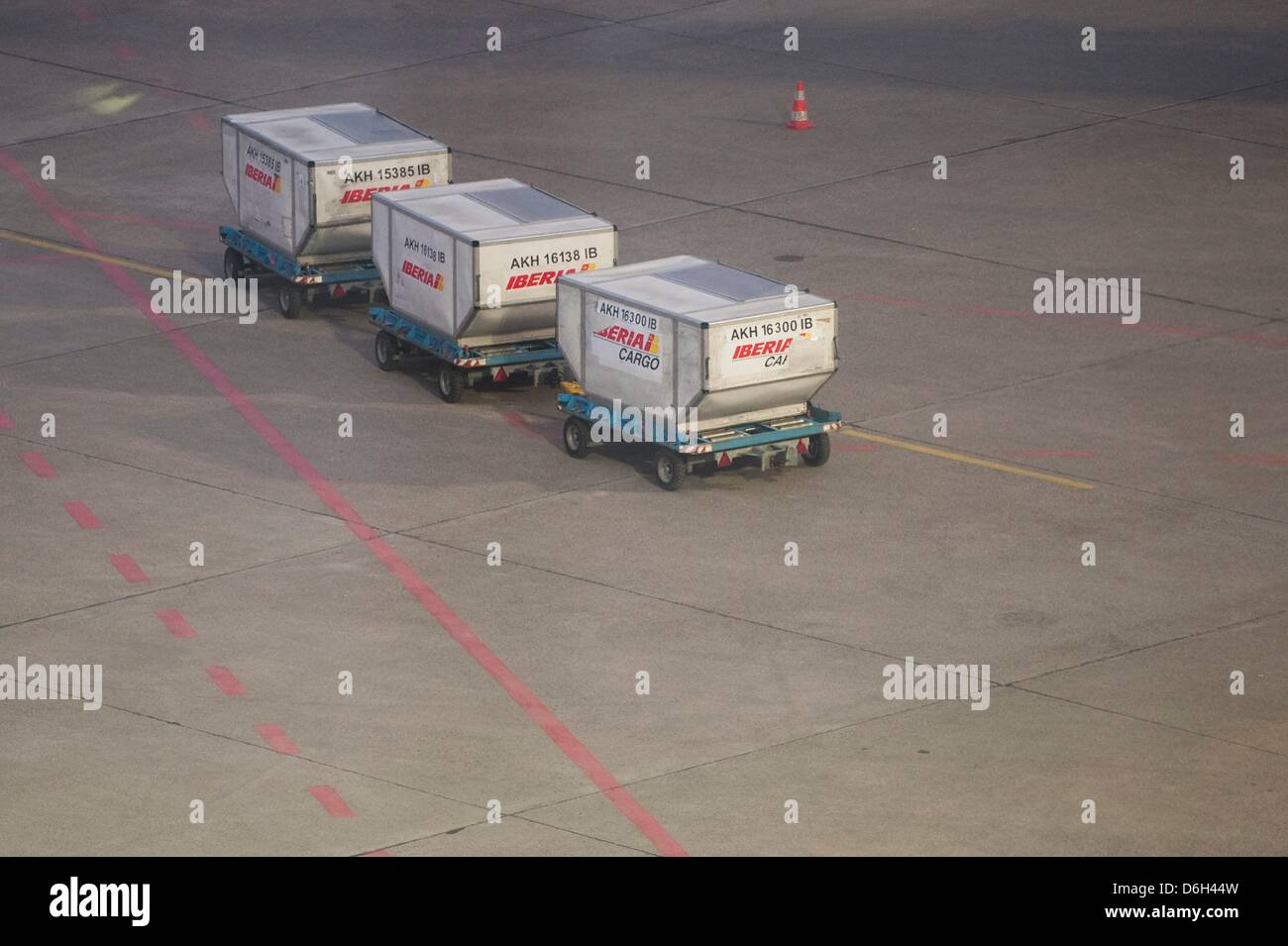 Baggage wagons are situated near the runway during a warning strike at
