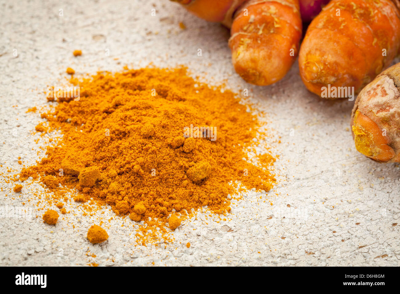 turmeric powder and root on a white painted rough barn wood surface Stock Photo