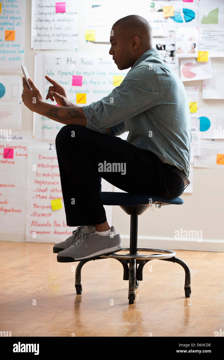 Man sitting on stool with digital tablet Stock Photo