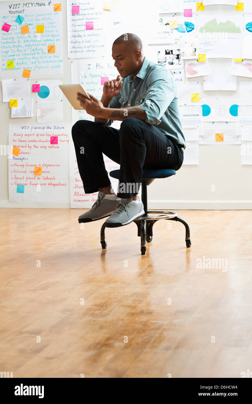 Man sitting on stool with digital tablet Stock Photo