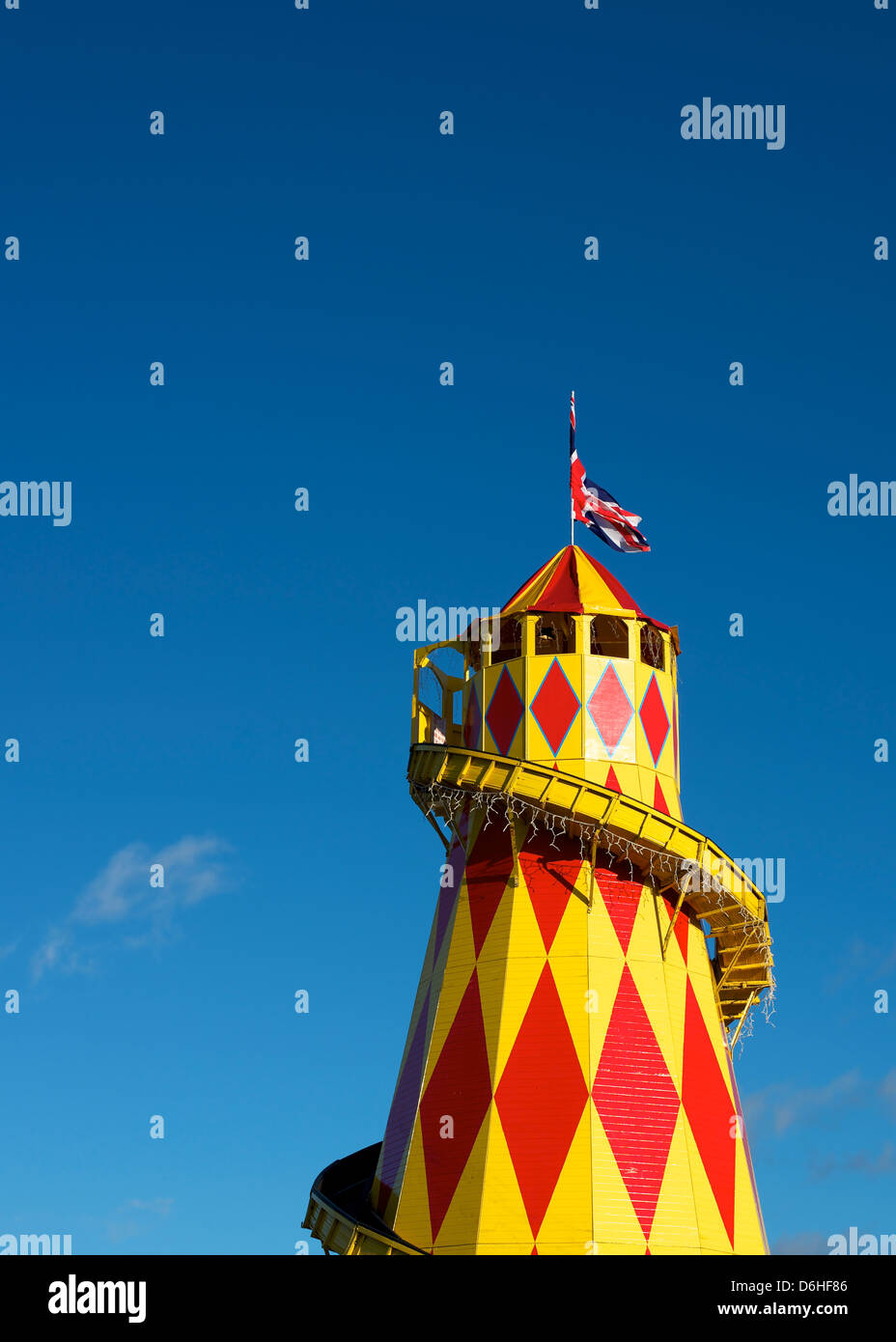 A Red and Yellow Helter Skelter funfair fairground attraction with a Union Flag set against a blue sky background Stock Photo