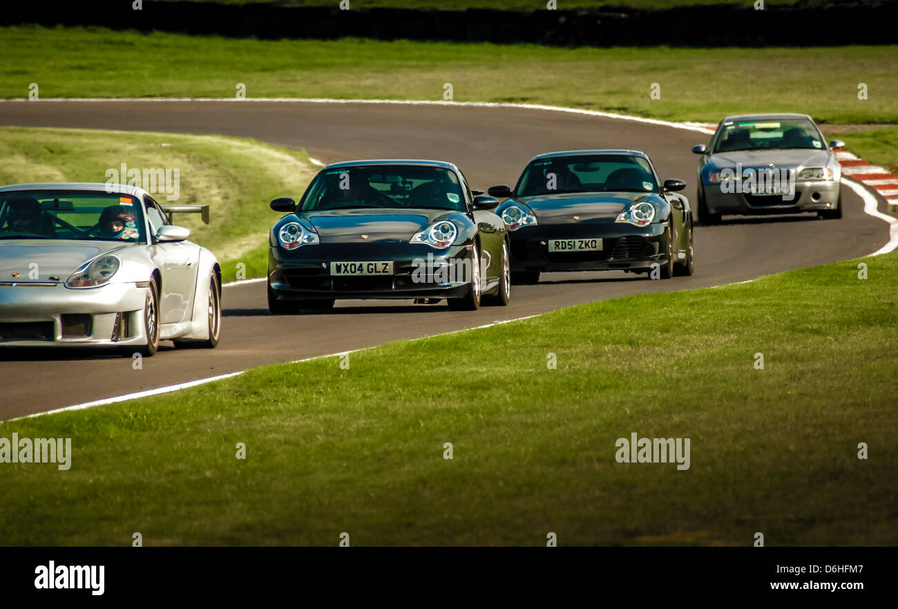 3 Porsche cars followed by a BMW car racing at Cadwell park race track Stock Photo