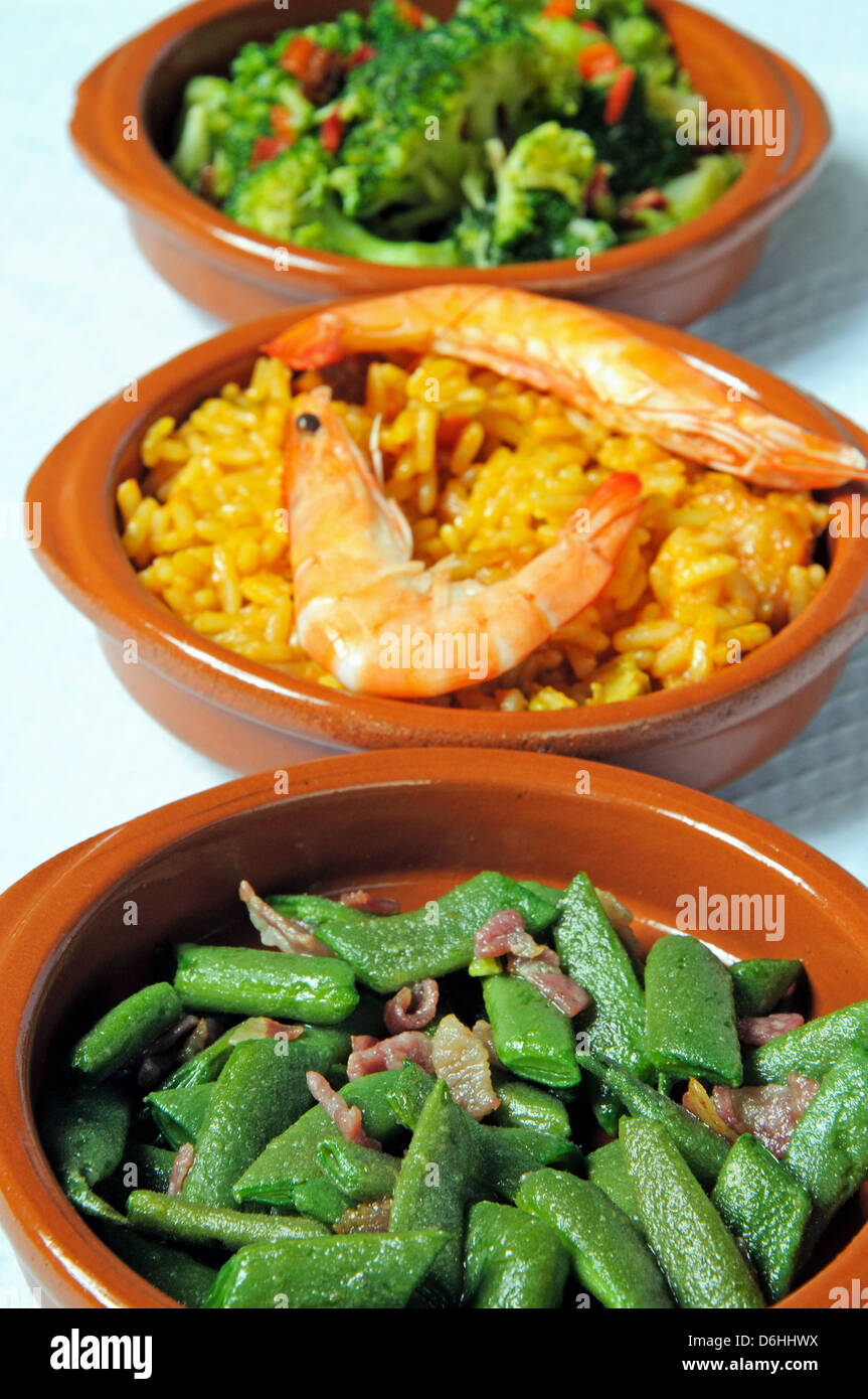 Tapas - Green beans with bacon, seafood and pork paella, broccoli with chilli and garlic, Stock Photo