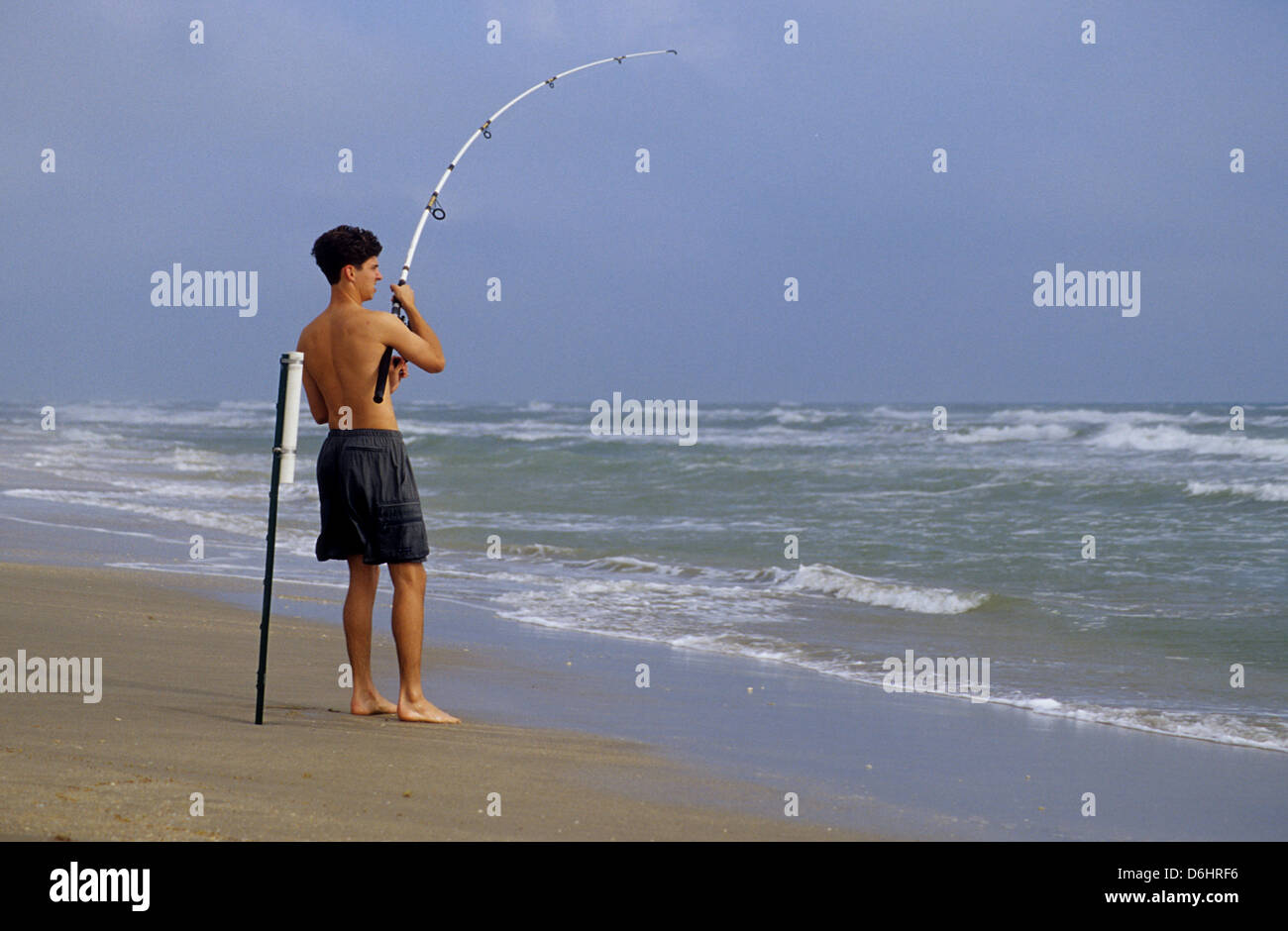 Surf fisherman reeling in a fish on North Padre Island Texas Stock Photo