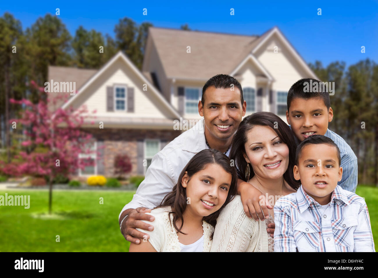 Happy Hispanic Family Portrait in Front of Beautiful House Stock Photo