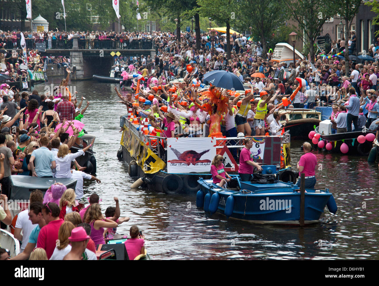 The Gay Pride Parade Down A Crowded Canal Lined With People And Boats