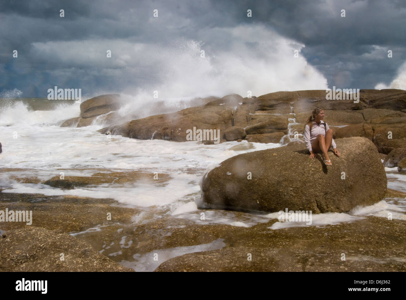 Girl on rock and surf on rocks near La Poloma in Rocha Uruguay Stock Photo