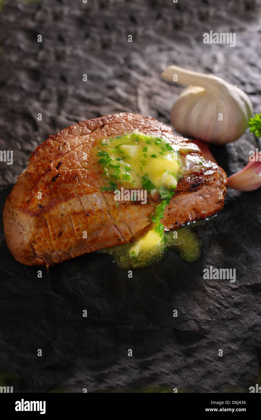 Fillet of steak with melted garlic butter on black slate Stock Photo