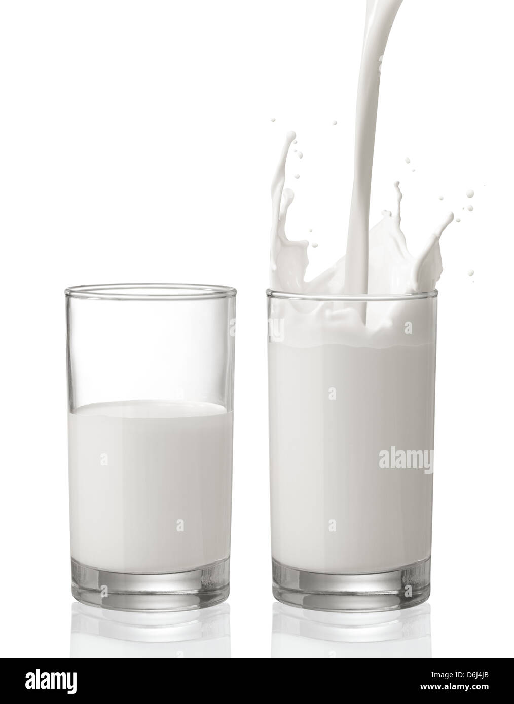 pouring milk creating splash with a glass of half full milk beside Stock Photo