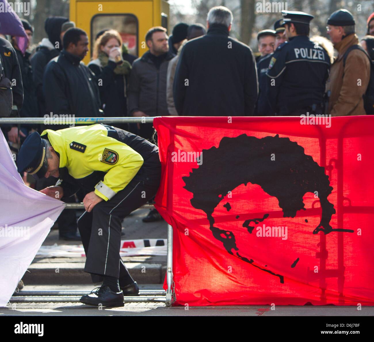 A police officer walks past a banner showing Oury Jalloh during a 