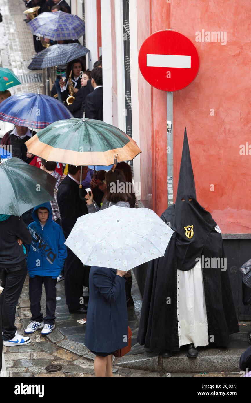 Penitent during Semana Santa (Holy Week) along rainy street, Seville, Andalucia, Spain, Europe Stock Photo
