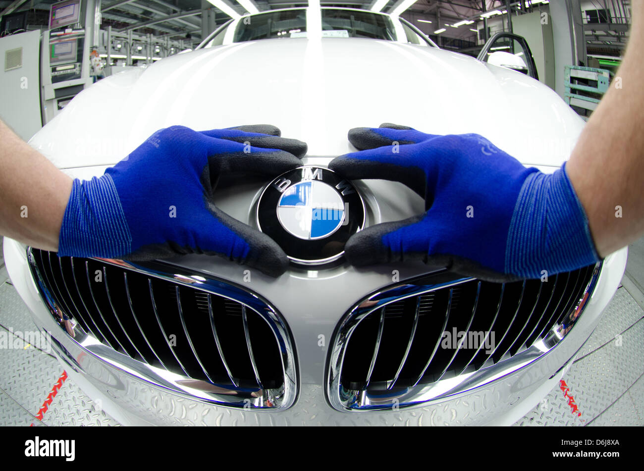 An employee puts a BMW logo onto the hood of a new BMW 3 at the factory in Regensburg, Germany, 07 March 2012. BMW has had the best year in the history of the company. Due to a record increase in sales the turnover has also reached a record high. Photo: ARMIN WEIGEL Stock Photo
