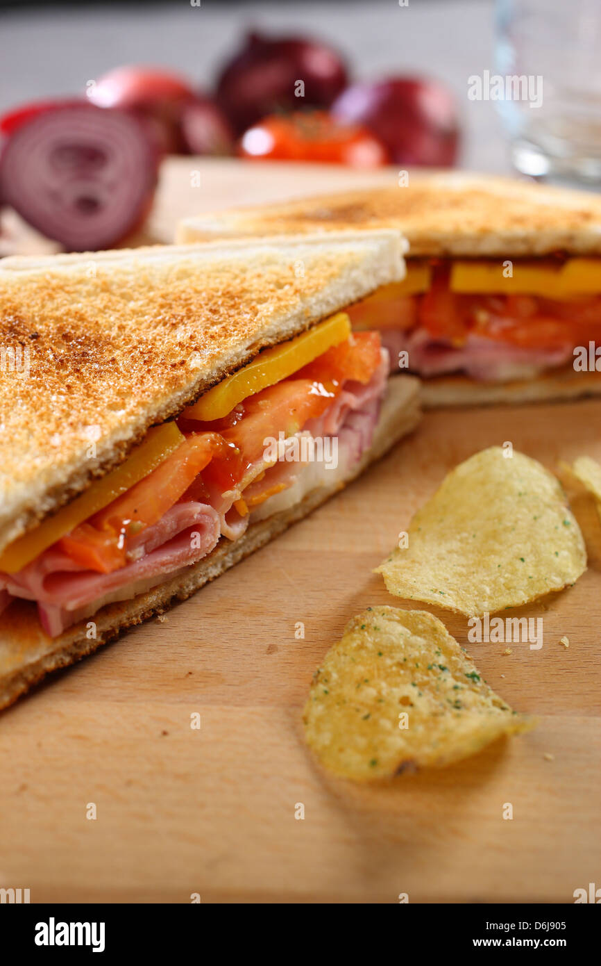 Portrait closeup of toasted ham cheese and tomato sandwich with crisps ...