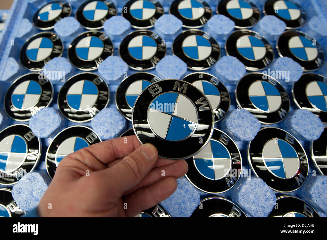 A hand holds a BMW emblem at the BMW factory in Regensburg, Germany, 07 March 2012. BMW hat the best year in the company's history thanks to record sails in 2011. Photo: ARMIN WEIGEL Stock Photo