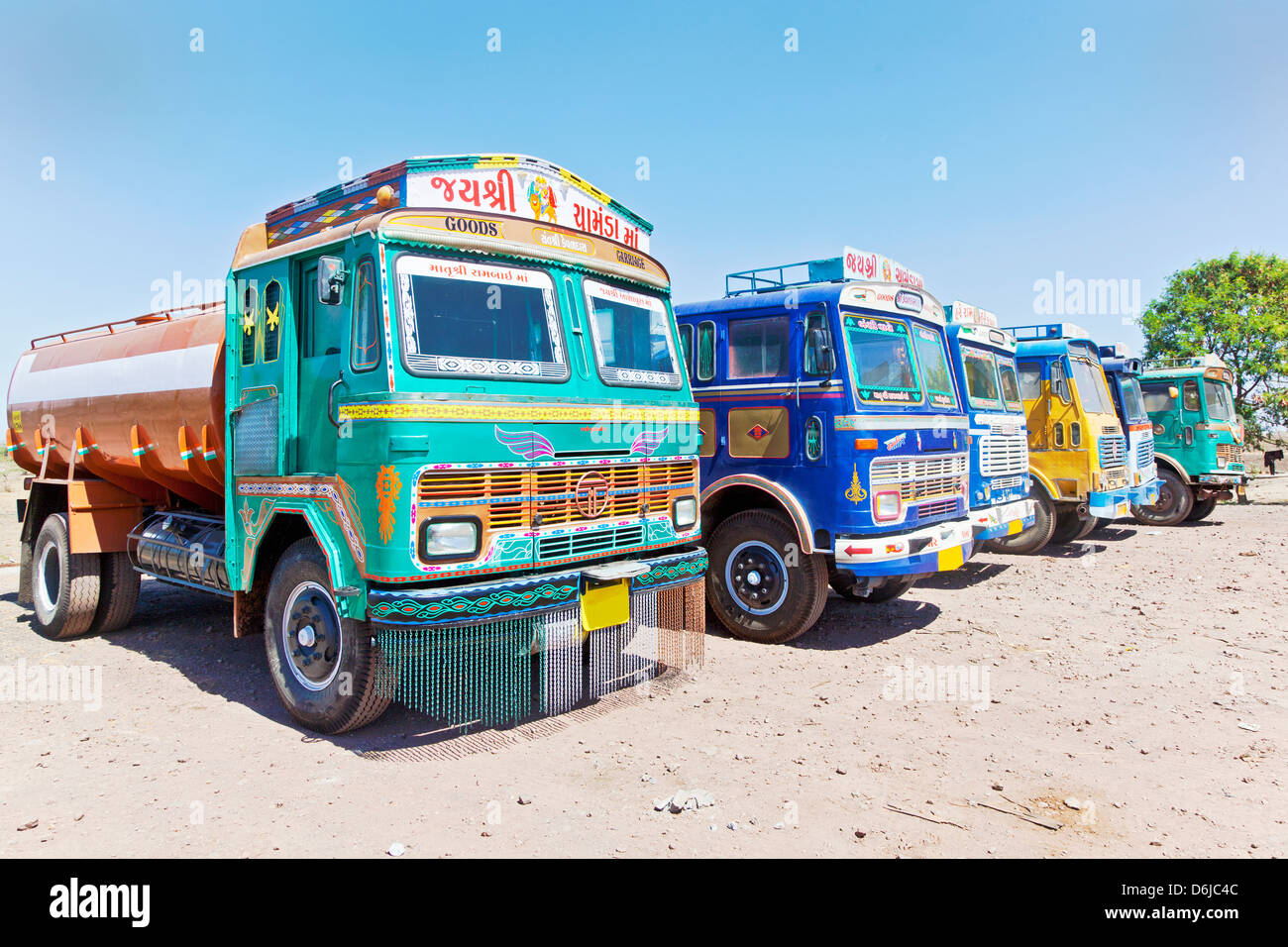 Colorful Indian heavy goods vehicles parked up at Dhabha (Indian truck stop) in the mid day sun Stock Photo