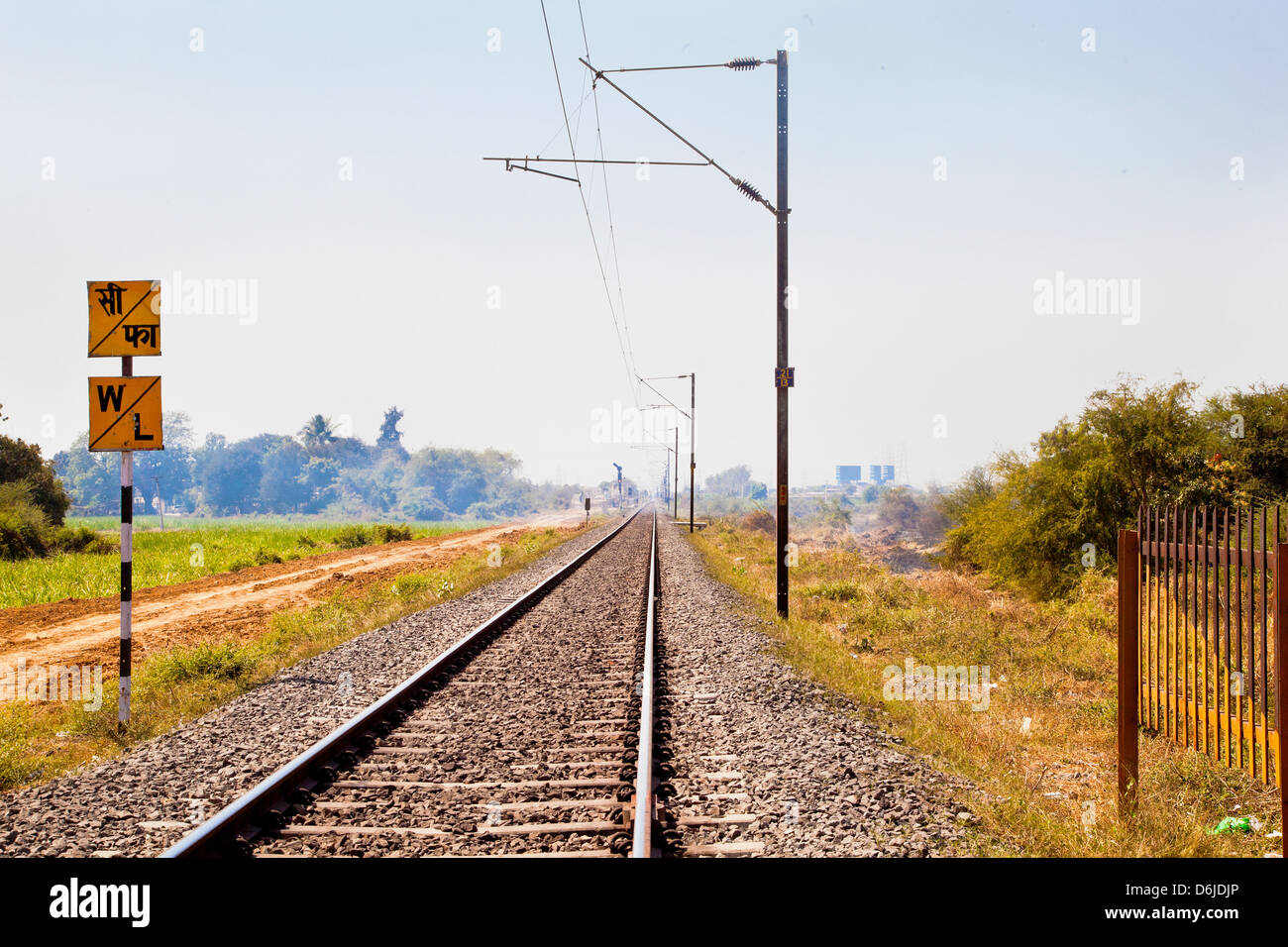 Railroad tracks in Indian cutting across the rural countryside along the outskirts of o Gujarat village towards the city of Stock Photo