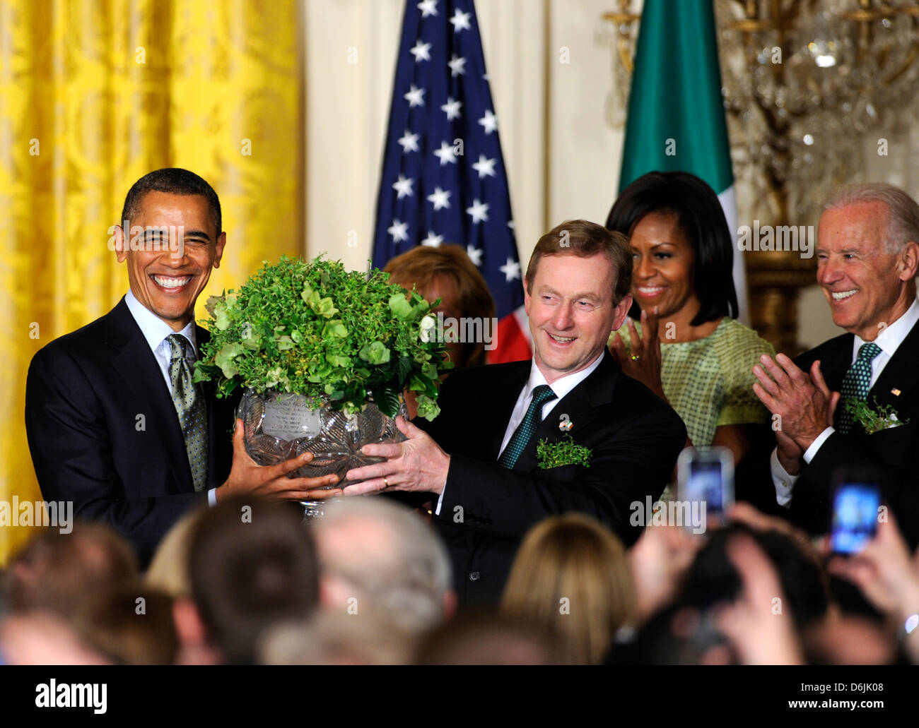 United States President Barack Obama (L) accepts a bowl of shamrocks from Irish Prime Minister Enda Kenny as first lady Michelle Obama (2nd,R) and Vice President Joe Biden (R) during a reception in the East Room of the White House, March 20, 2012, in Washington, DC. The two leaders concluded a working day devoted to discussions on economic matters, Ireland's peace keeping participa Stock Photo