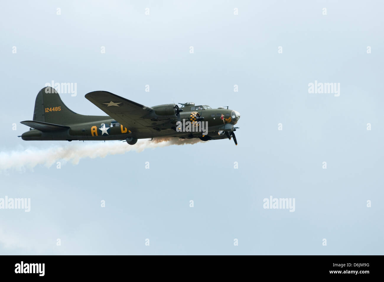 A World war two USAF B17 aircraft performs a fly past trailing smoke, isolated against a grey sky. Stock Photo