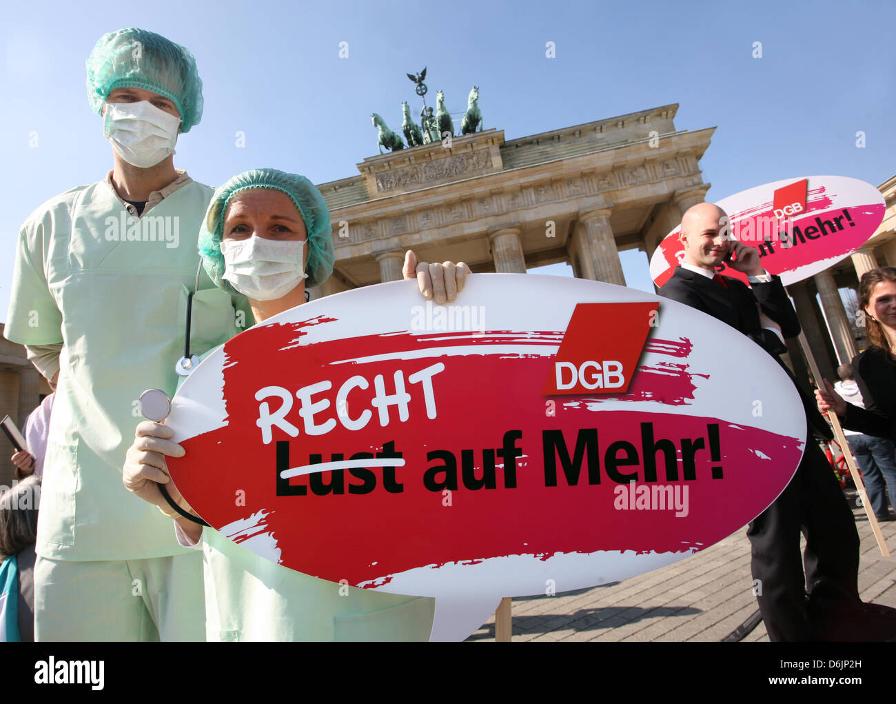 Two protesters dressed in medical gowns hold up a sign which reads 'Recht auf Mehr!' (Rights to more!) during the 'Equal Pay Day' rally in front of the Brandenburg Gate in Berlin, Germany, 23 March 2012. The rally took place on the occasion of the International Women's Day under the motto 'Recht statt billig - Entgeldgleichheit gesetzlich regeln' (Equal rights instead of cheap - fo Stock Photo