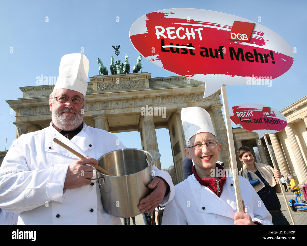 Two protesters dressed as chefs hold up a sign which reads 'Recht auf Mehr!' (Rights to more!) during the 'Equal Pay Day' rally in front of the Brandenburg Gate in Berlin, Germany, 23 March 2012. The rally took place on the occasion of the International Women's Day under the motto 'Recht statt billig - Entgeldgleichheit gesetzlich regeln' (Equal rights instead of cheap - for legal  Stock Photo