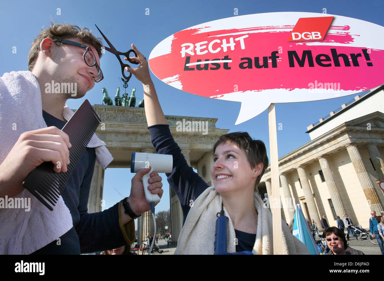 Two protesters dressed as hairdressers hold up a sign which reads 'Recht auf Mehr!' (Rights to more!) during the 'Equal Pay Day' rally in front of the Brandenburg Gate in Berlin, Germany, 23 March 2012. The rally took place on the occasion of the International Women's Day under the motto 'Recht statt billig - Entgeldgleichheit gesetzlich regeln' (Equal rights instead of cheap - for Stock Photo