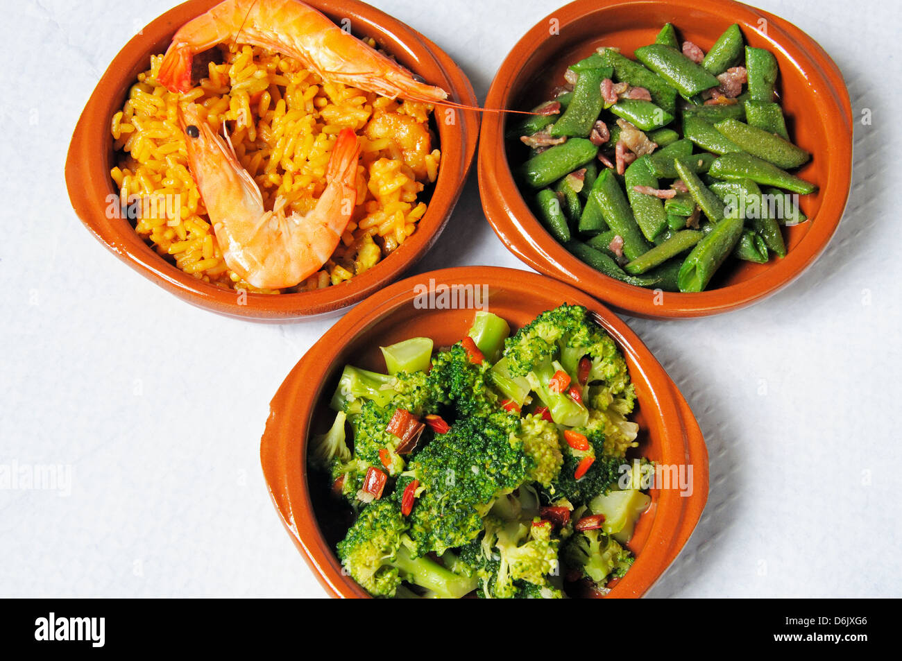 Tapas - Seafood and pork paella, broccoli with chilli and garlic, green beans with bacon. Stock Photo