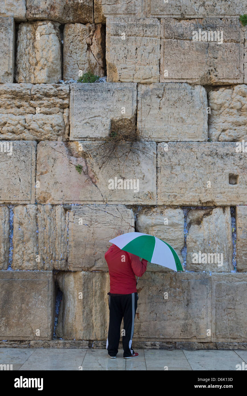 man with umbrella praying alone at the Western Wall. Jerusalem Old City. Israel. Stock Photo