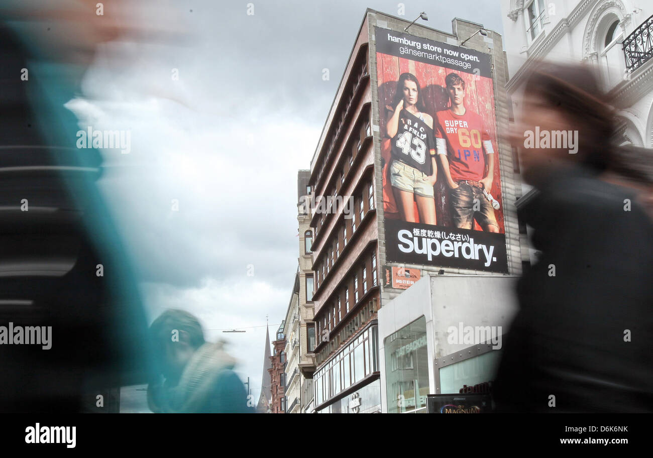 Passers-by cross the street next to a giant 'Superdry' advertisement in  downtown Hamburg, Germany, 26
