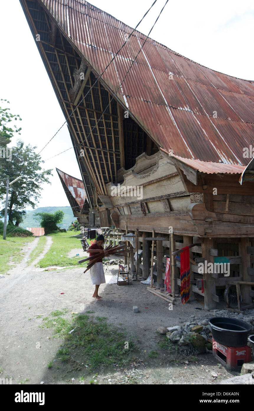 Batak woman carrying yarn to the looms under her Batak house, Buhit, Samosir Island, Lake Toba, Sumatra, Indonesia Stock Photo