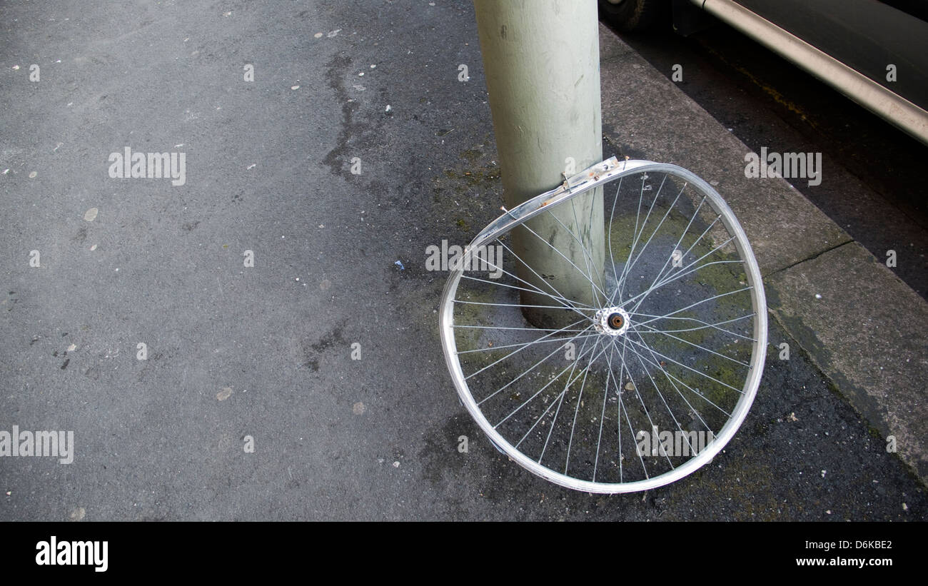 Bent, abandoned bicycle wheel against lampost Stock Photo Alamy