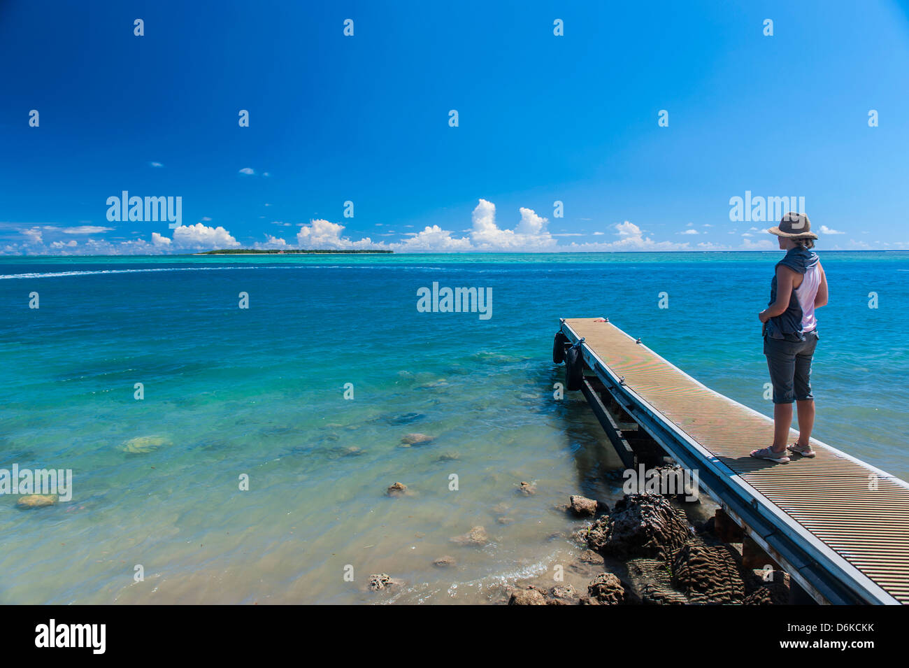 Tourist standing on a little pier with Cocos Island in the distance, Guam, US Territory, Central