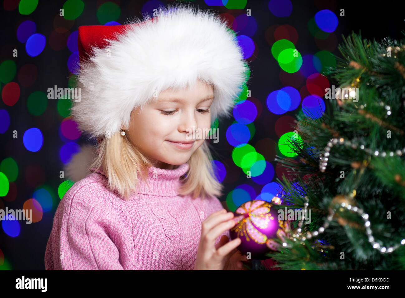 pretty preschool girl decorating Christmas tree over bright festive background Stock Photo