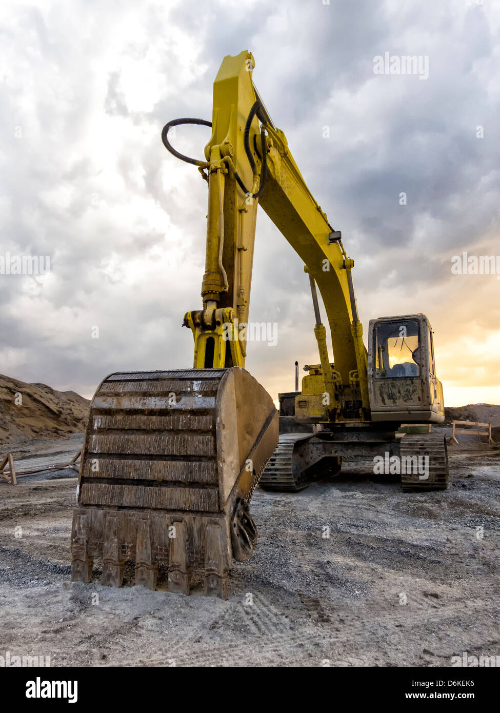 Yellow excavator loader machine at construction site over a cloudy sky Stock Photo