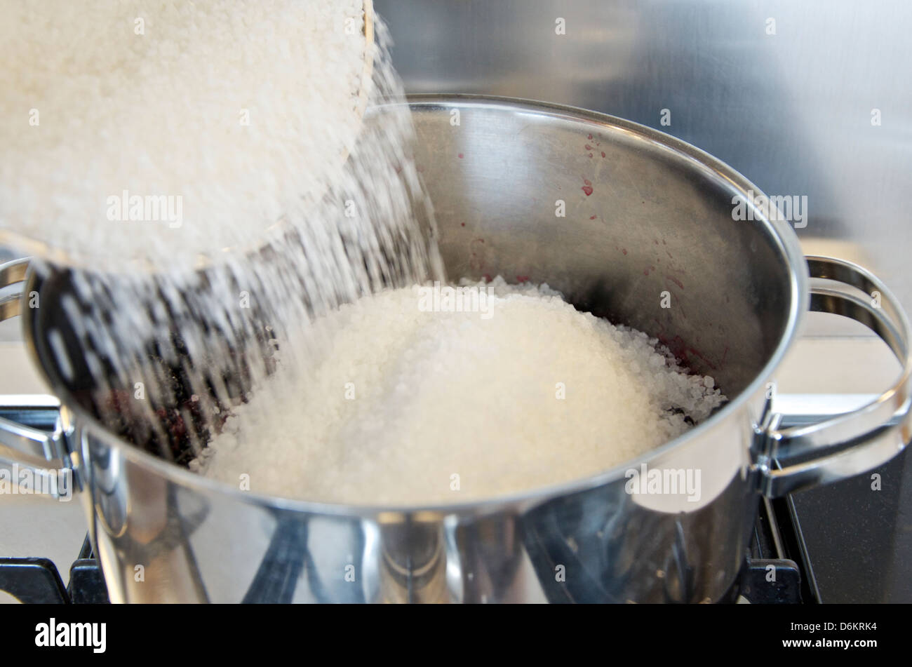 Making Jam: Step 6/10, adding preserving sugar to stainless steel pan of blackberries. Stock Photo