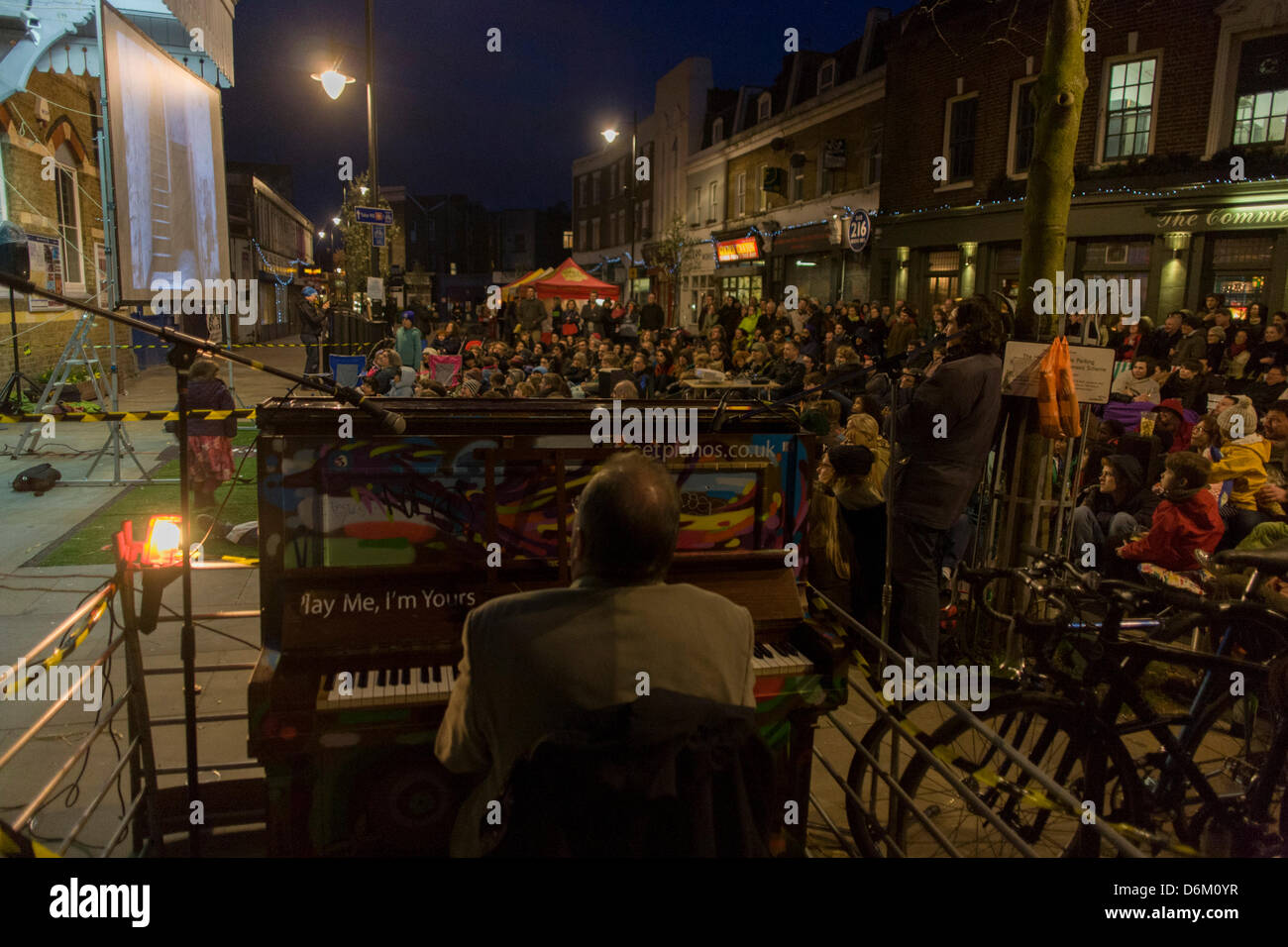 London, UK. 19th April, 2013.  Accompanied by a pianist, south Londoners sit outside their rail station on whose wall is a screening of the silent film Easy Street starring a former local boy, Charlie Chaplin, kicking off a series of the Free Film Festival in Herne Hill in the London borough of Lambeth. There is no official record of his birth although Chaplin believed he was born at East Street in nearby Walworth. Credit Richard Baker / Alamy Live News Stock Photo