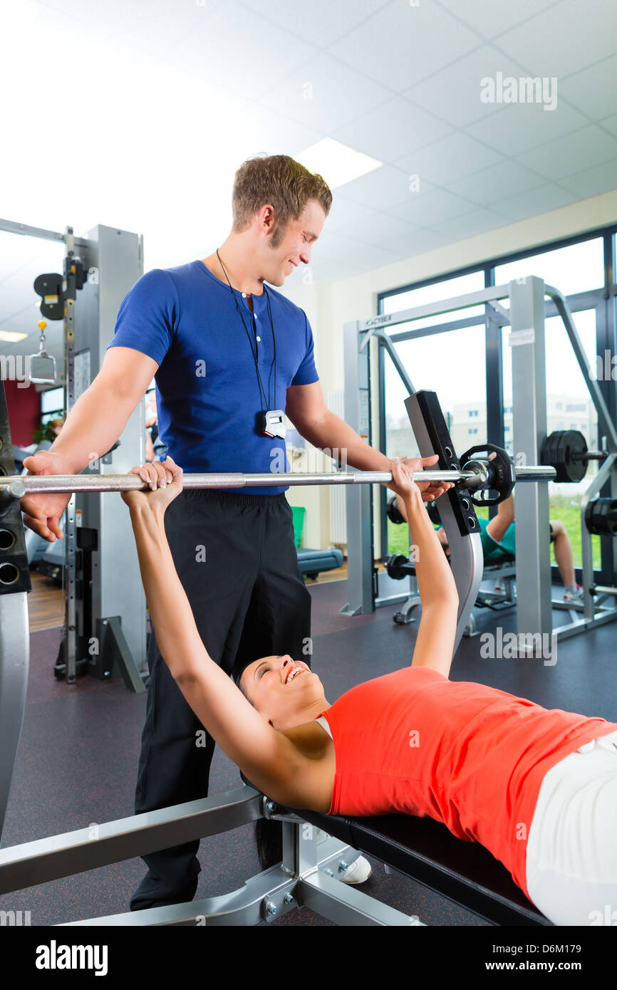 Woman with her personal fitness trainer in the gym exercising with ...