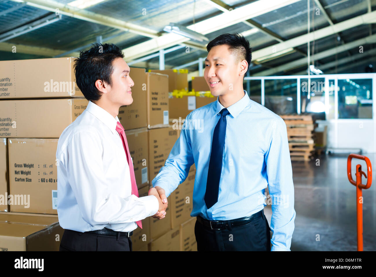 Manager, owner or businessmen in a warehouse of a forwarding agency or a factory shake hands Stock Photo