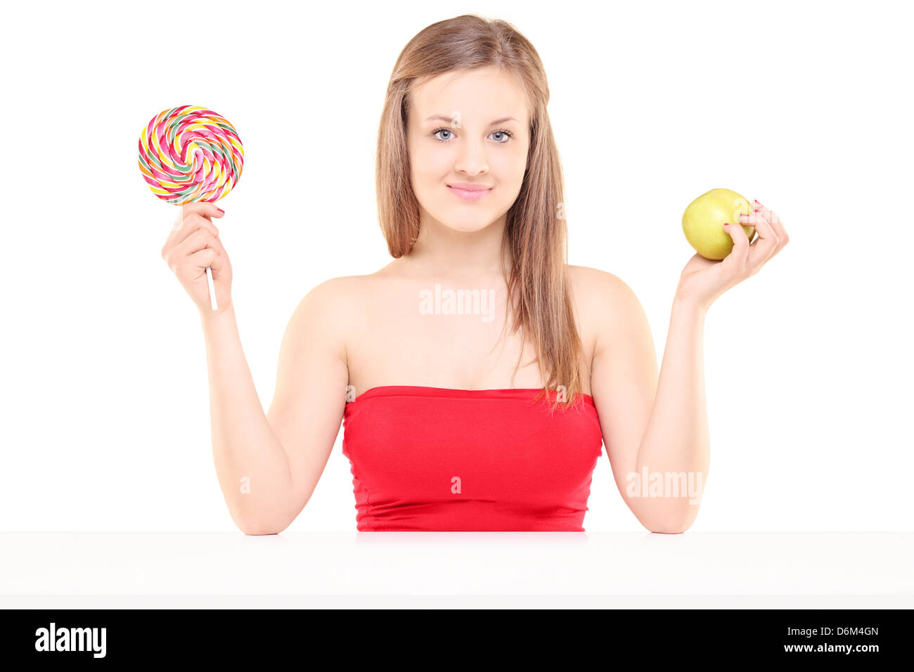Pretty young girl holding a lollipop and an apple, isolated on white background Stock Photo