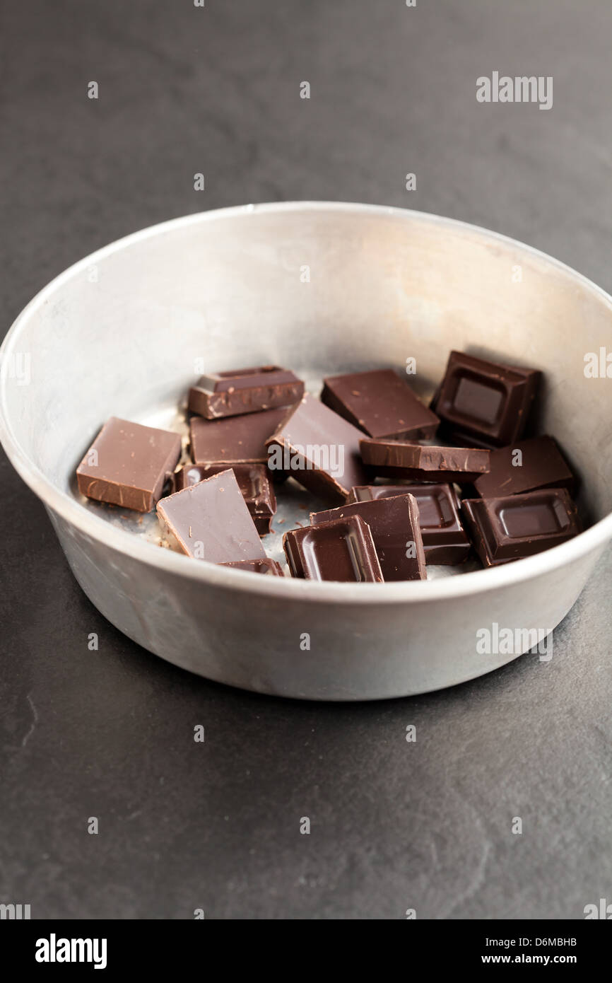 Closeup of bowl containing pieces of chocolate on dark background Stock Photo