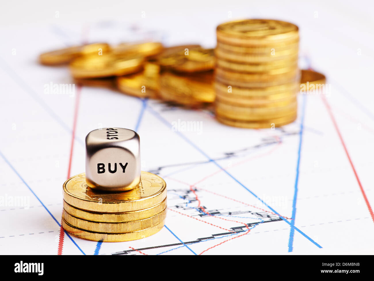 Stacks of coins, dices cube with word BUY and a up trend chart as the background. Successful trading. Selective focus Stock Photo